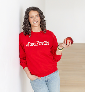 Maria in a #RedForEd sweater holding an apple